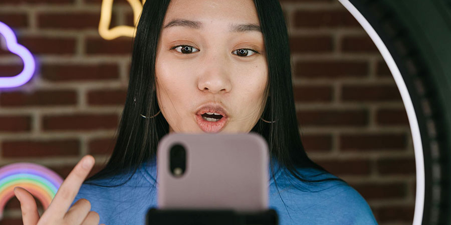 woman in front of a ring light and a smartphone recording herself talking